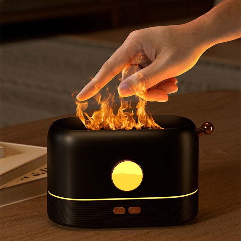 A Black USB simulation flame humidifier with a flame effect on top, emitting vapor. A hand inside the vapor demonstrates the vapor is cool to the touch